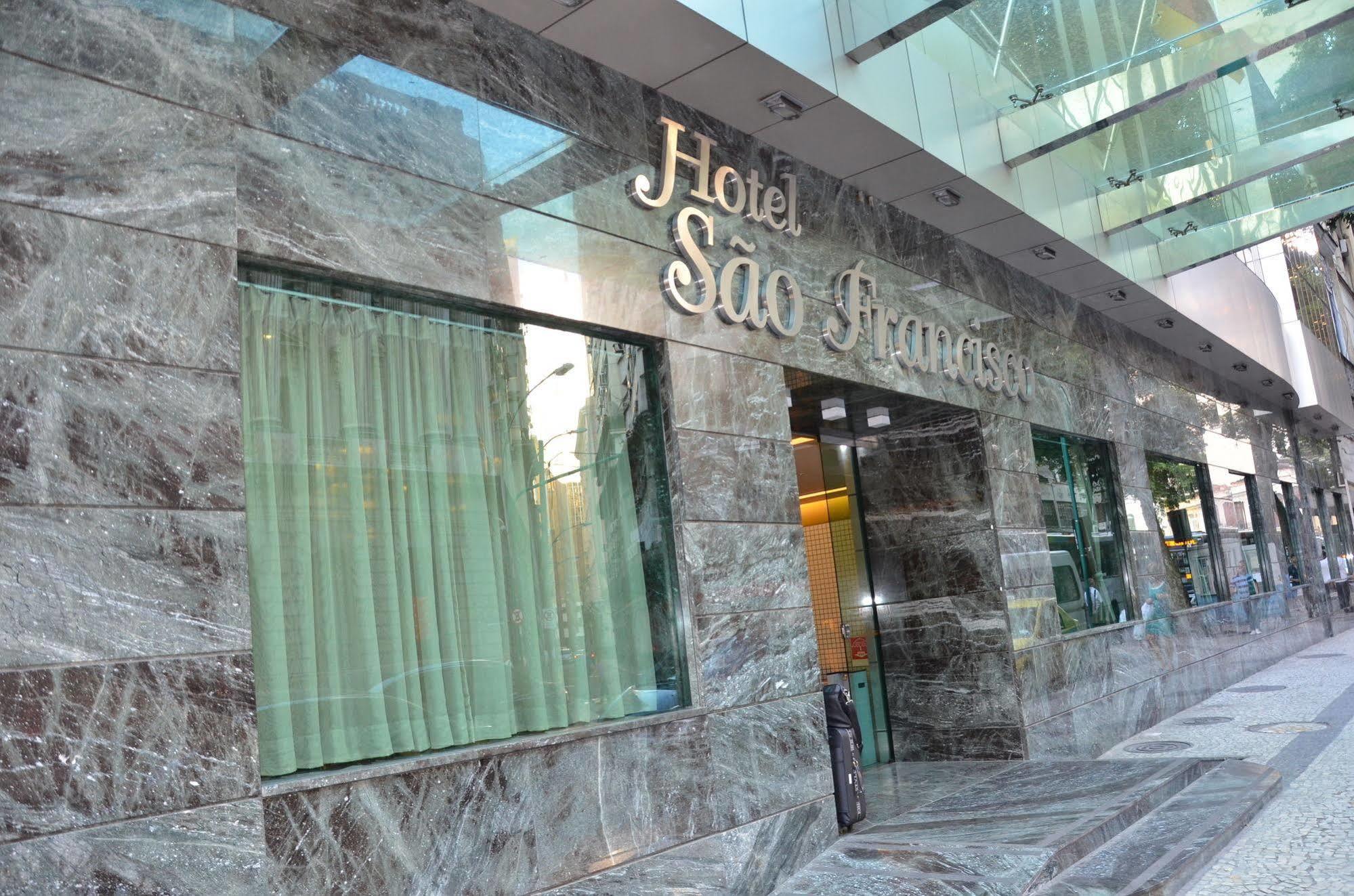 Hotel Atlantico Tower Rio de Janeiro Buitenkant foto The photo shows the exterior of a hotel named "Hotel São Francisco." The facade is made of marble, giving it an elegant appearance, and large glass windows are visible, likely allowing natural light to enter the interior. There are light green curtai